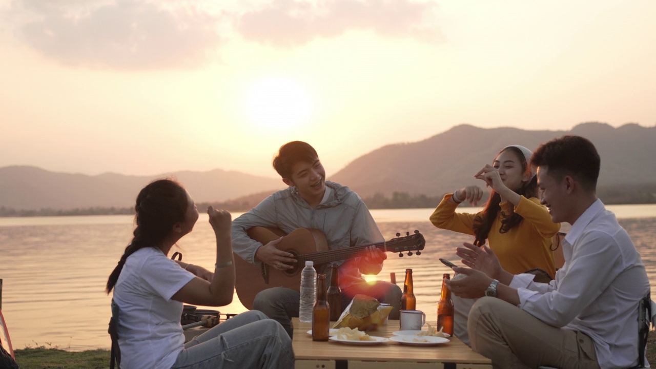 一群快乐的亚洲朋友在露营时弹吉他、唱歌视频下载