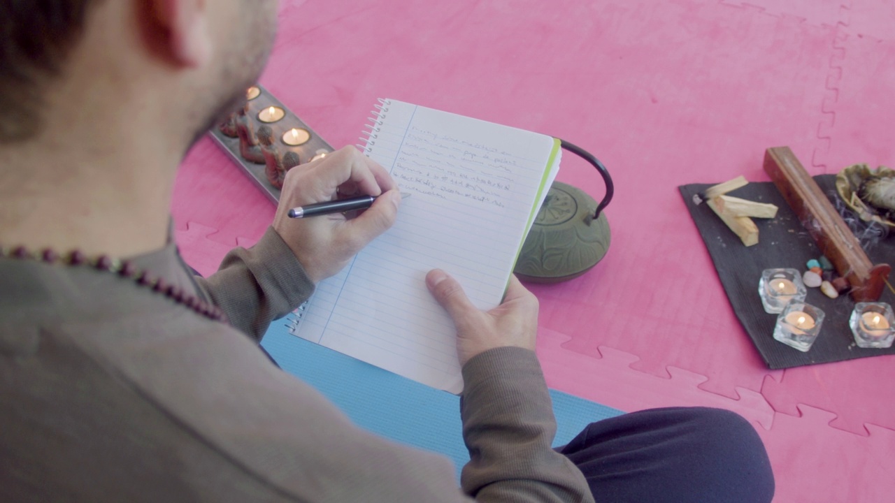 男人坐在莲座上，在笔记本上写东西视频素材