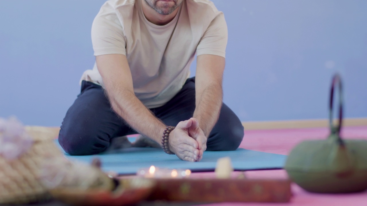 男人坐在地板上，拿着香练习瑜伽视频素材