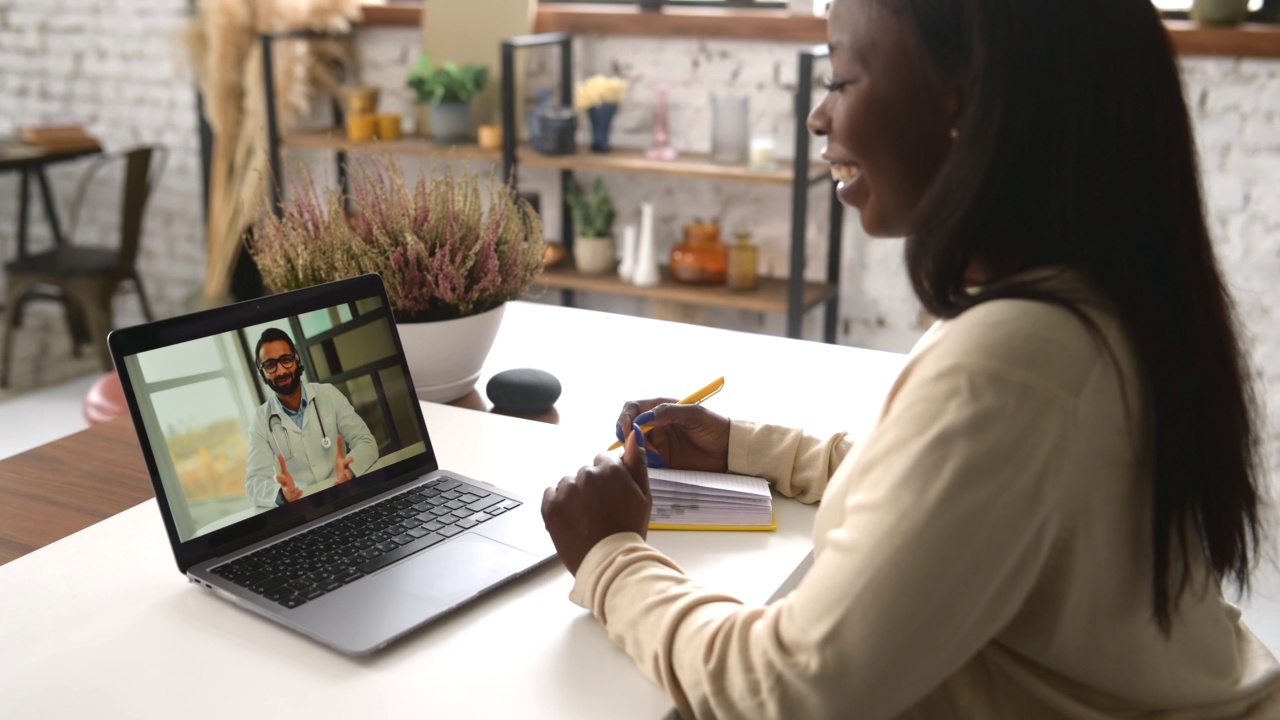 非裔美国女性在家与医生在线交谈，进行虚拟医疗检查视频下载