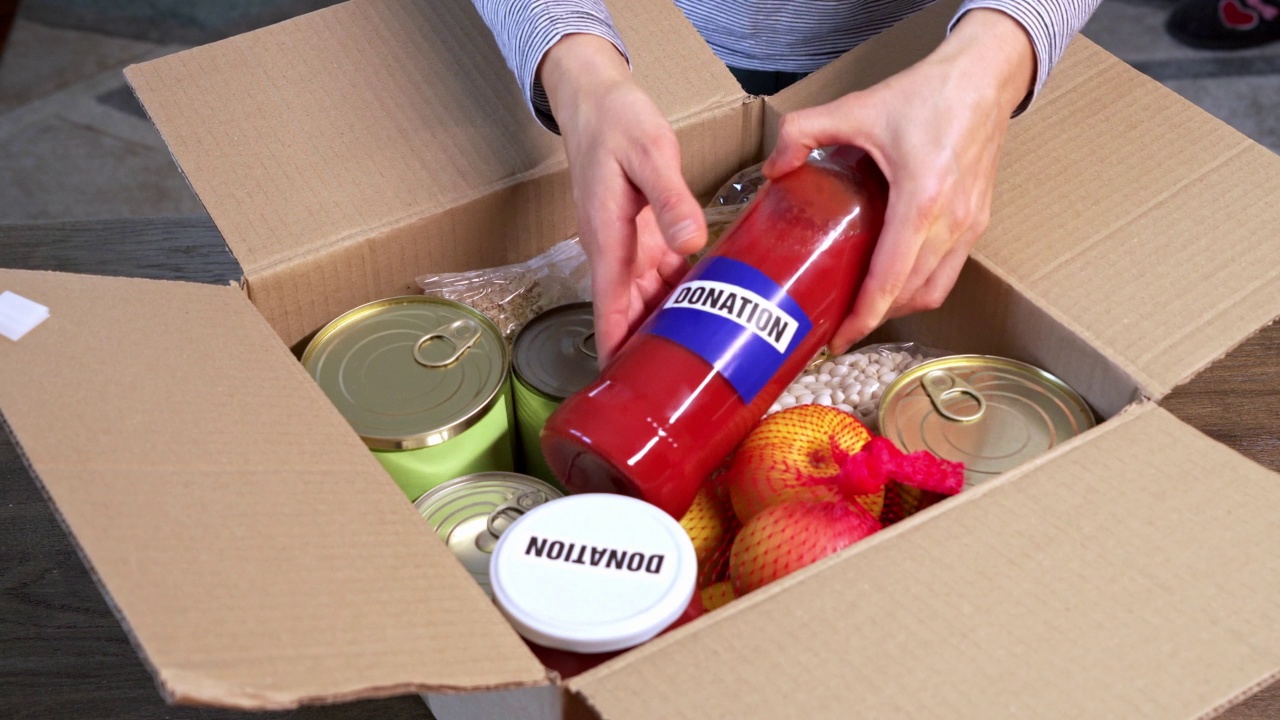 一个陌生的人正在往盒子里装食物，给需要的人捐赠视频素材