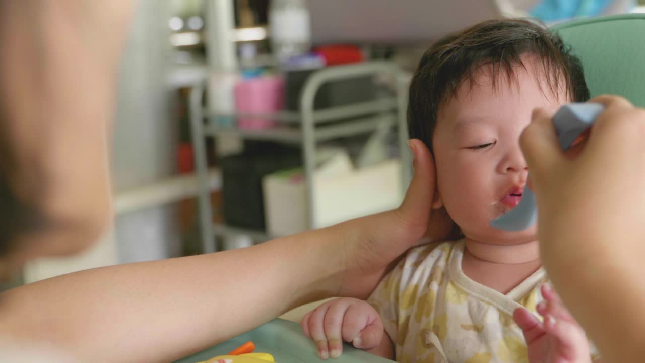 可爱的亚洲宝宝在椅子上吃婴儿食品。视频素材