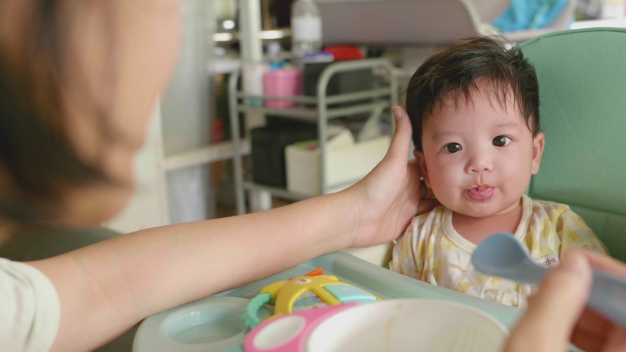 可爱的亚洲宝宝在椅子上吃婴儿食品。视频素材