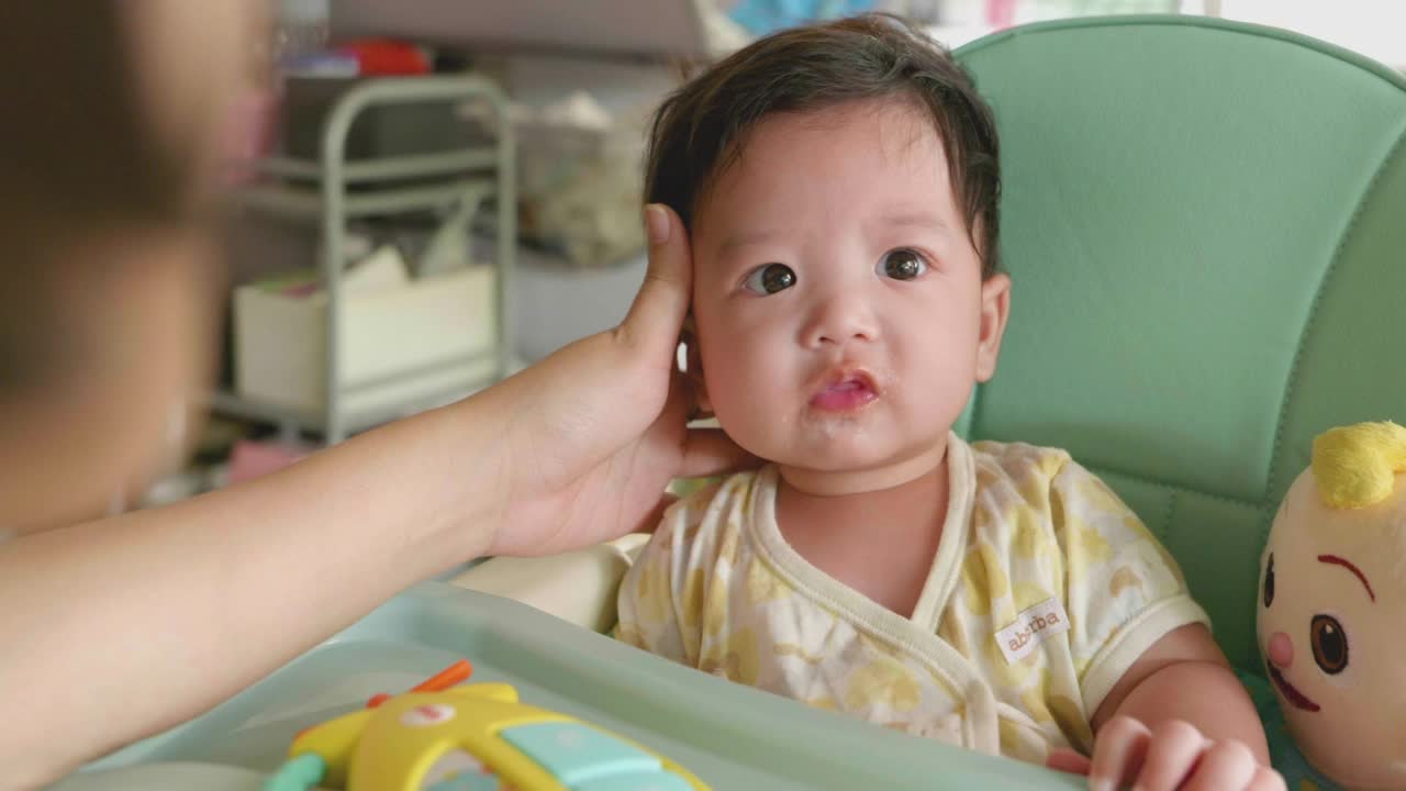 亚洲妈妈用手喂她的小男孩食物。视频素材