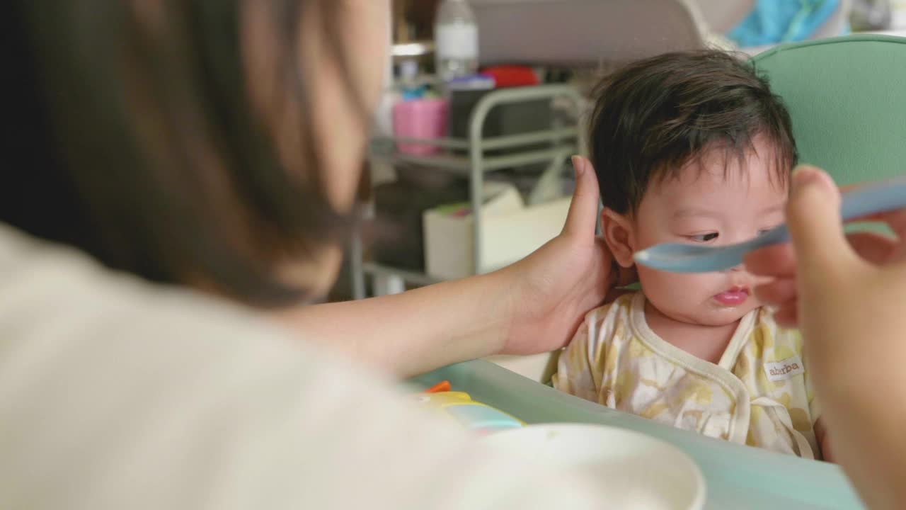 亚洲妈妈用手喂她的小男孩食物。视频素材