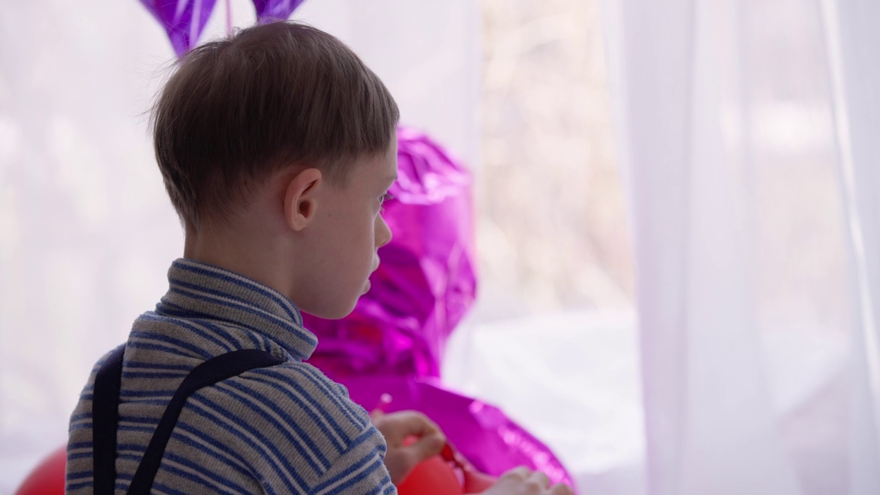 微笑的自闭症古玩男孩在室内玩彩色气球。可爱的白人婴儿出生异常精神疾病和玩具在家里休息。生活方式和自闭症的概念。视频素材