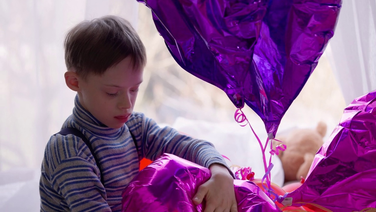 一名自闭症男孩在家里玩充气气球。侧面的古玩肖像快乐轻松的婴儿出生异常享受休闲与玩具。自闭症和好奇心。视频素材