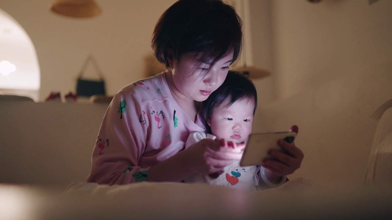 亚洲母亲和女儿在床上使用智能手机视频素材