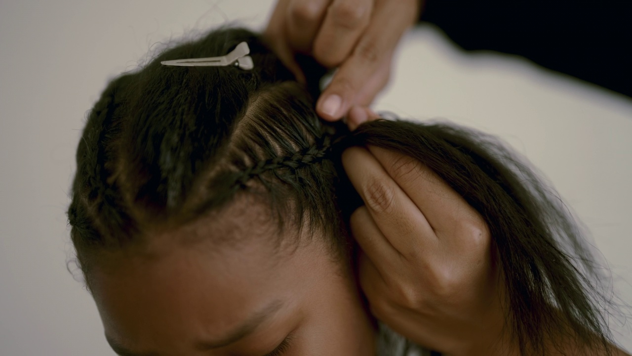 一个黑人女孩正在给她的美发师编辫子。视频素材