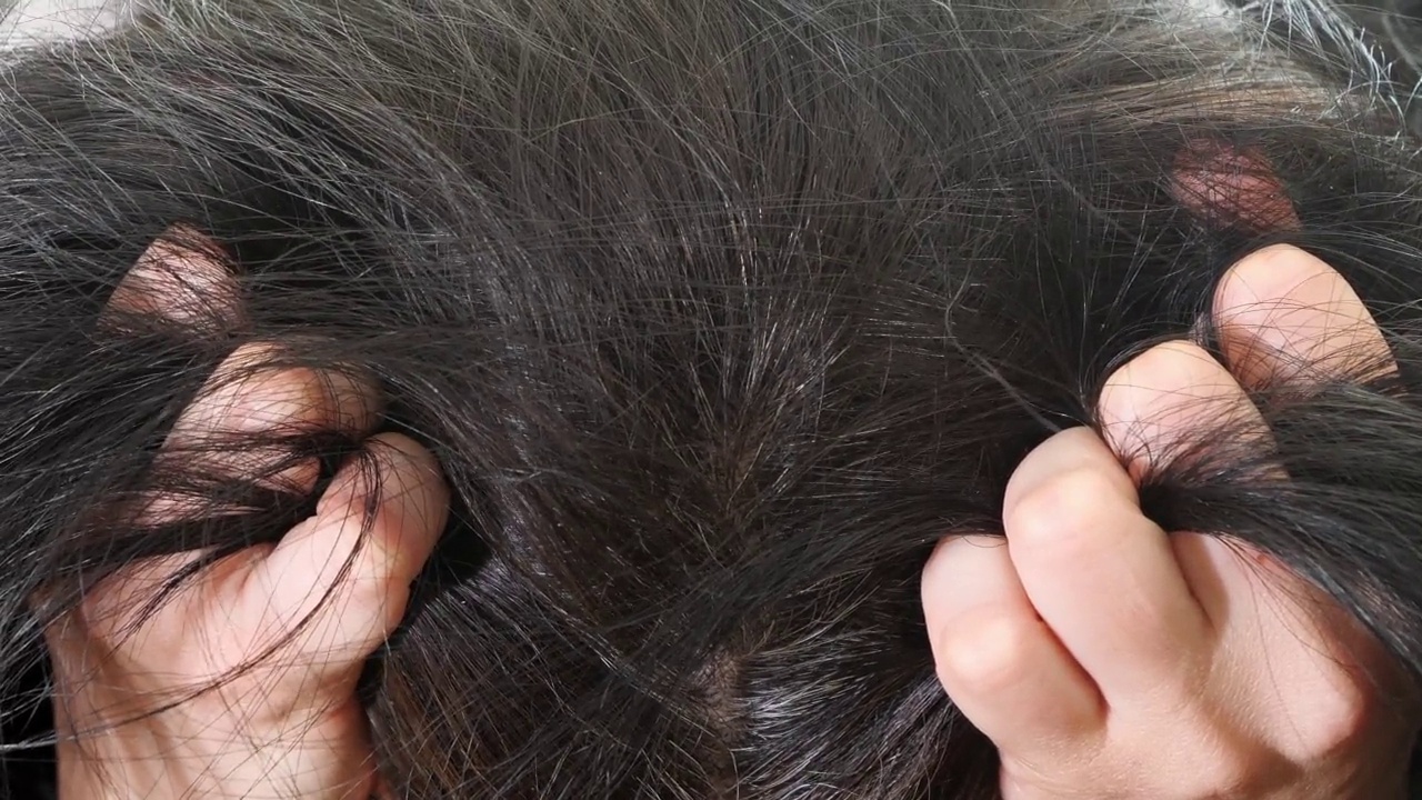 担心难过的女人。中年妇女摸着她的黑色头发和灰色的发根。近距离视频素材