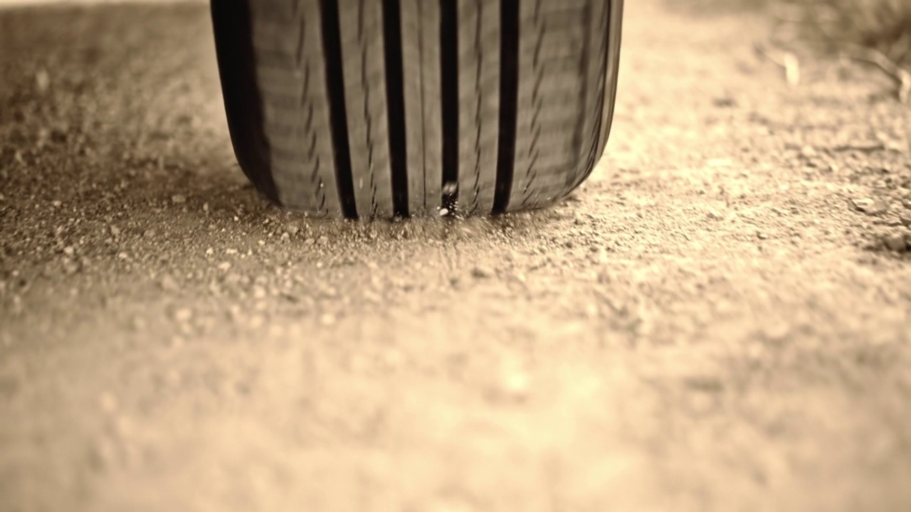 一辆汽车的轮胎在砾石路上扬起灰尘视频下载