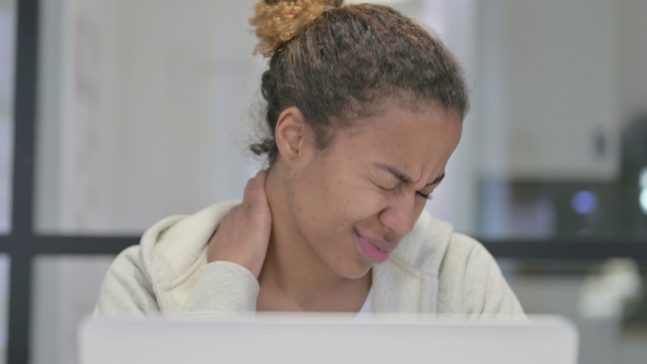 非洲妇女在使用笔记本电脑时颈部疼痛的特写视频下载