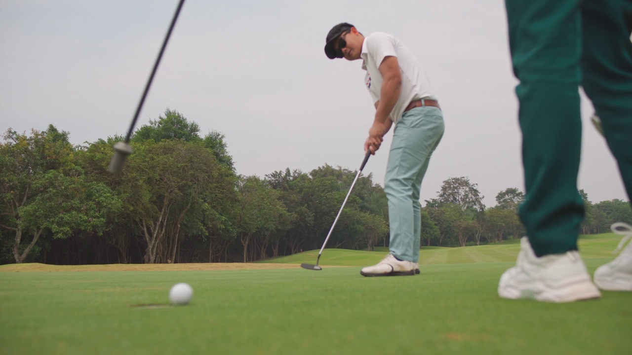 4K亚洲男子高尔夫球，在高尔夫球道上正把球传洞视频素材