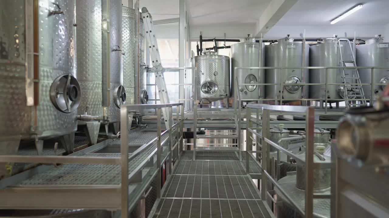 酒精生产工厂室内广角镜头。不锈钢酒桶在制造工厂发酵饮料。缓慢的运动。视频下载