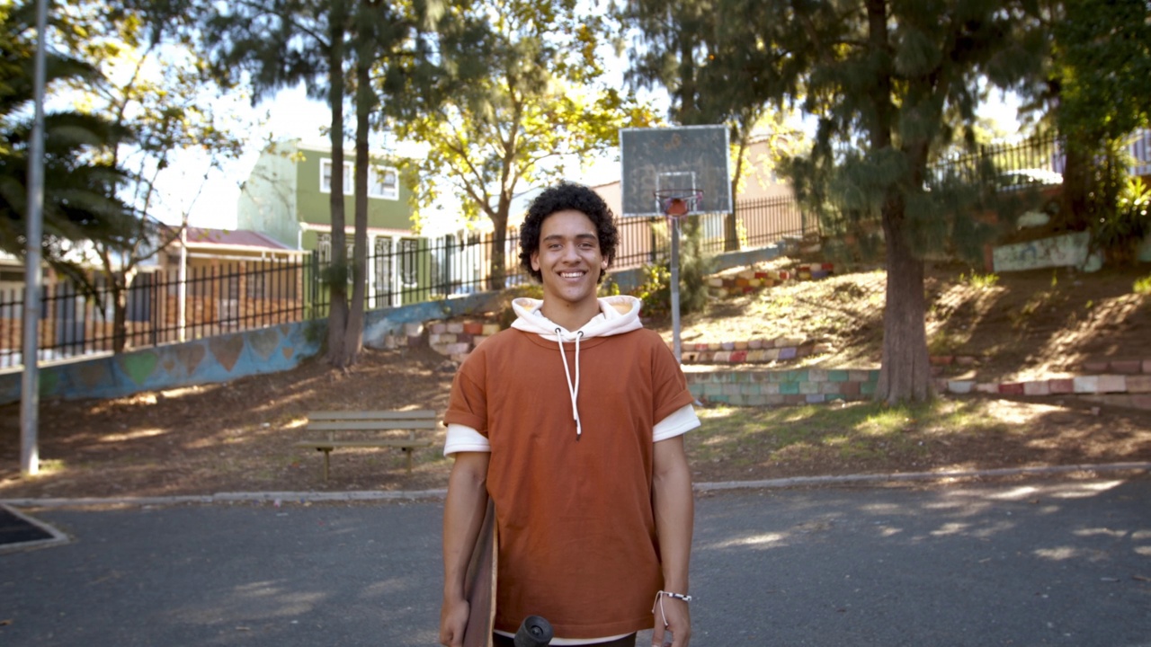 十几岁的滑板手站在外面微笑视频素材