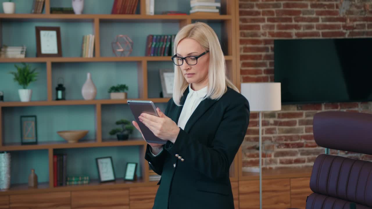 专业的女商务经理持有使用数字平板电脑技术的在线办公站在现代办公室。商务现代办公场所技术视频下载