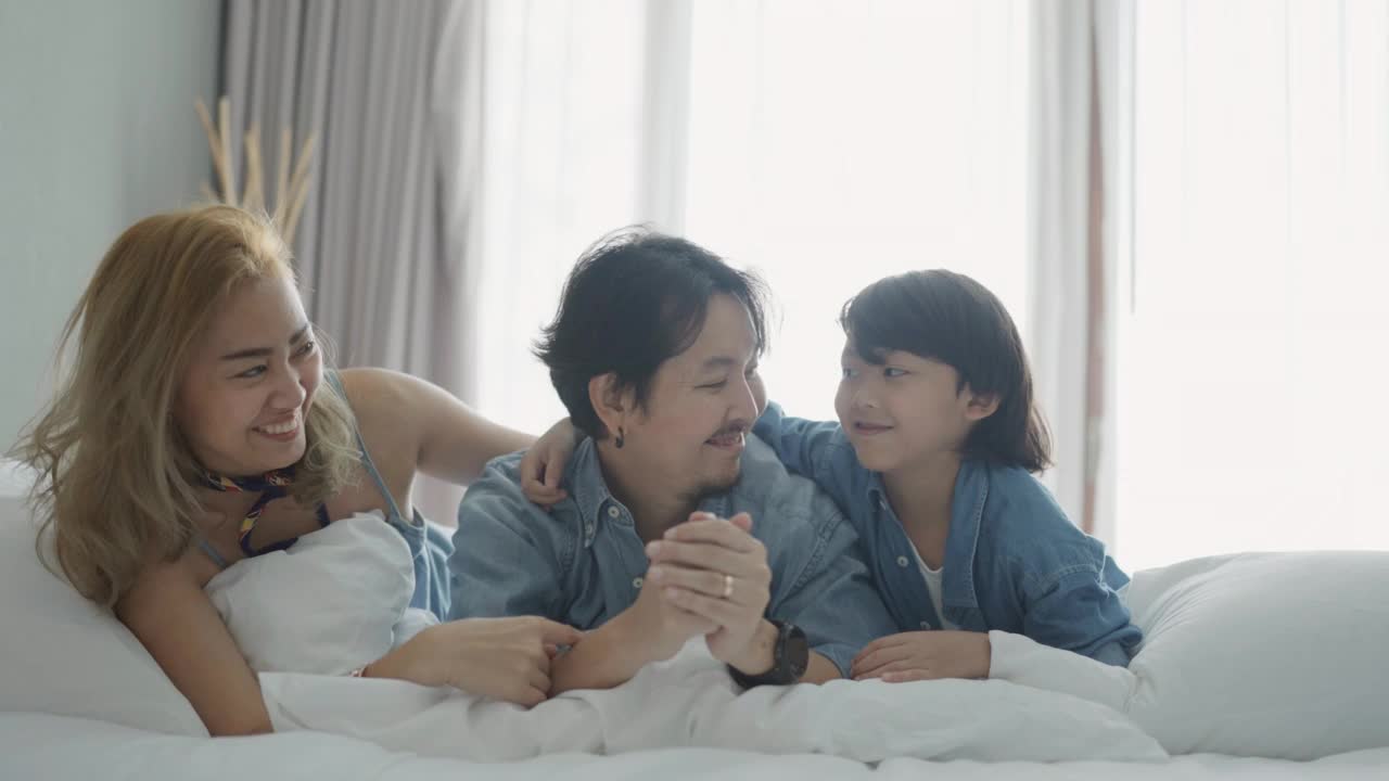 微笑的家人一起在床上玩耍视频素材