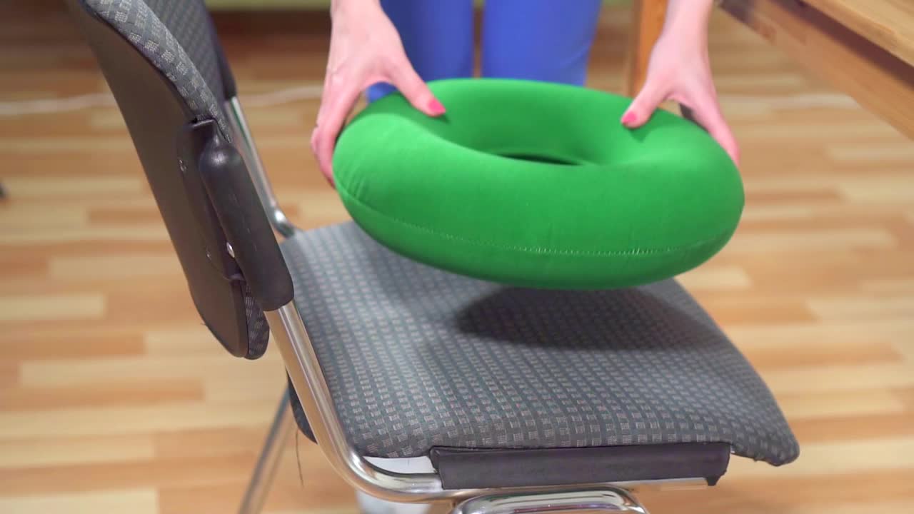 一个穿着衬衫的女人坐在一个绿色的整形枕头上，慢慢地近距离工作视频下载