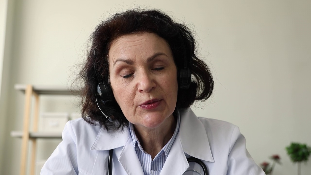 戴着耳机的女医生通过视频电话采访病人视频下载