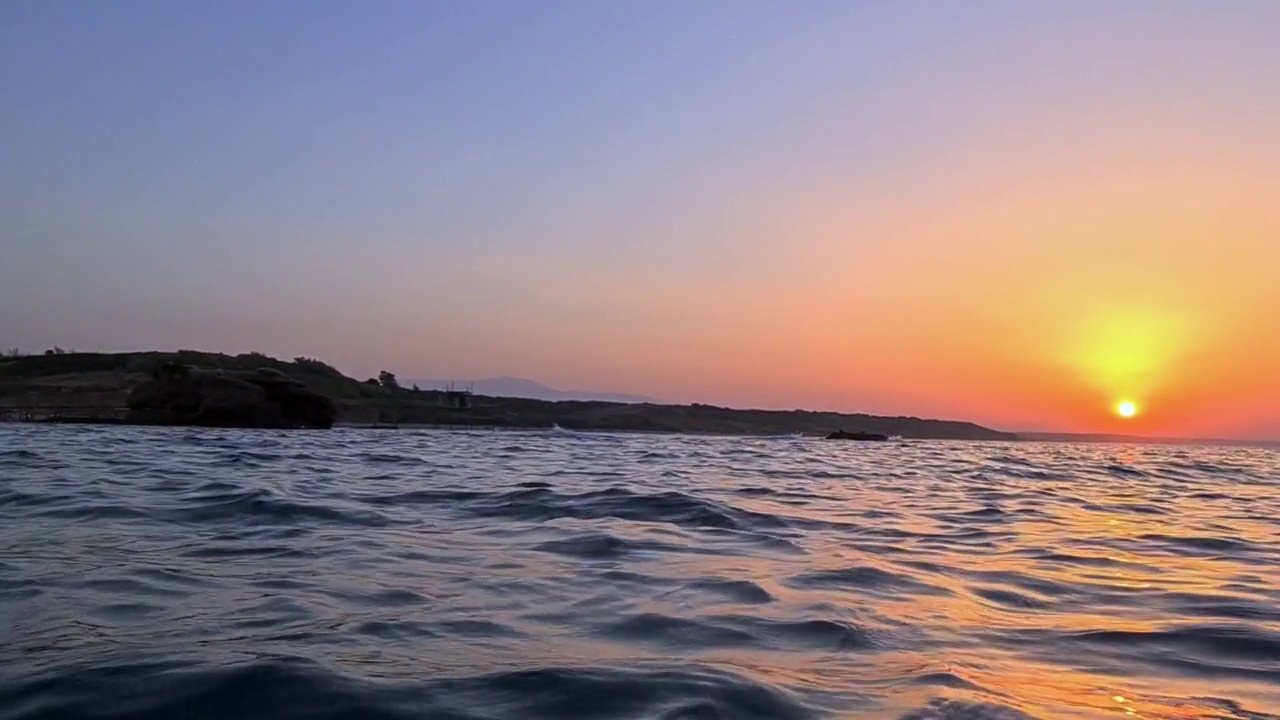 极低的角度在海水表面移动走向惊人的日落。慢动作视频素材