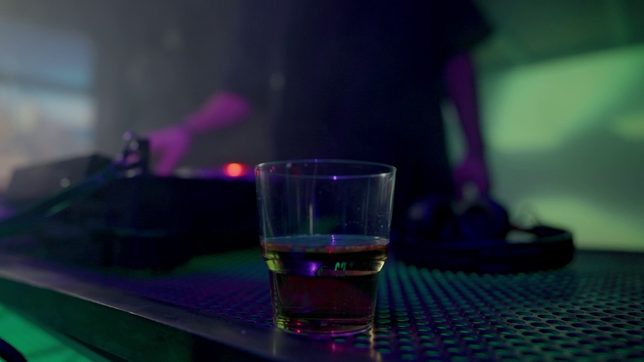 DJ工作在控制台与一杯酒的前景视频下载