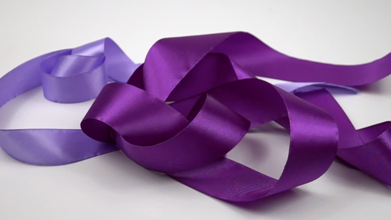 紫色和粉色缎带躺在白色背景上，慢镜头视频下载
