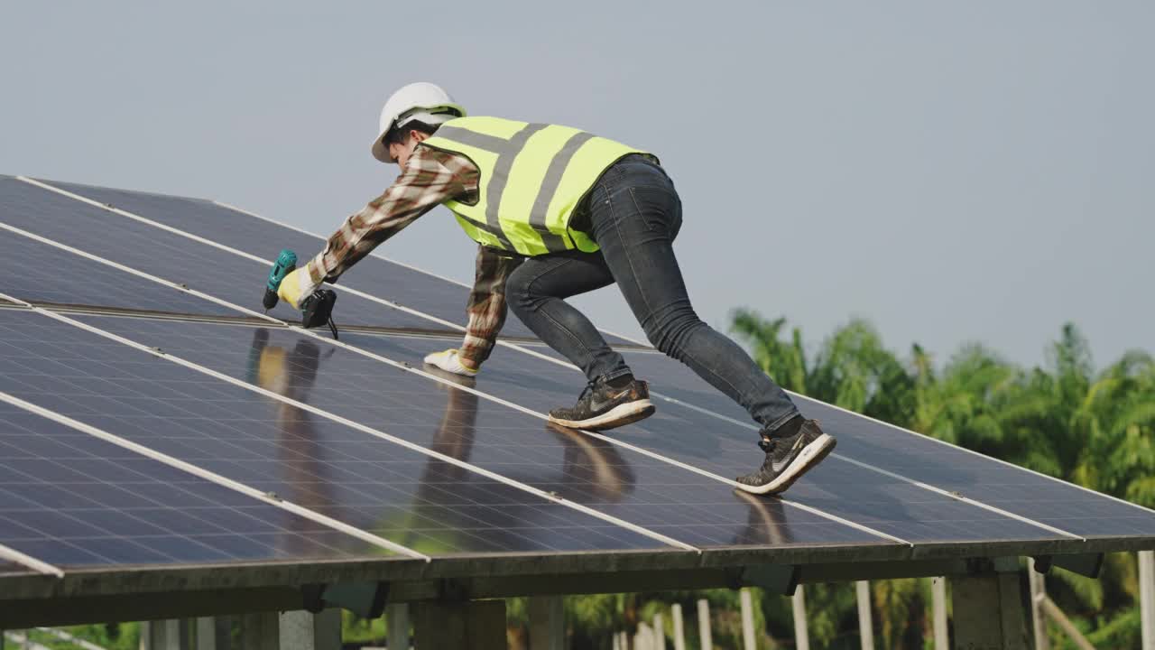 年轻的亚洲男性在屋顶光伏太阳能发电厂的光伏面板上工作视频素材