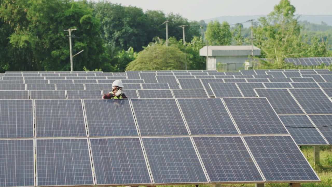 年轻的亚洲男性在屋顶光伏太阳能发电厂的光伏面板上工作视频素材