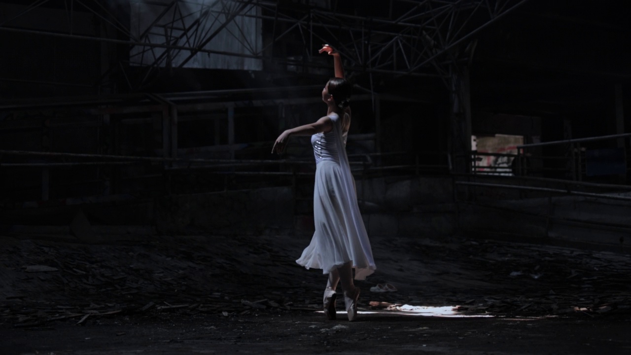 年轻美丽的芭蕾舞女演员在黑暗中与烟背光跳舞。视频素材