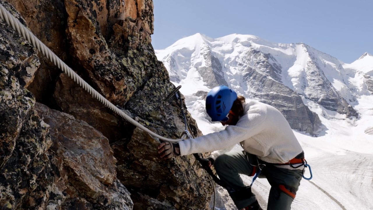 一个人在高山上的小径上，用他的方式攀岩到山顶。男登山者在Via Ferrata路线上，上面是冰川视频下载
