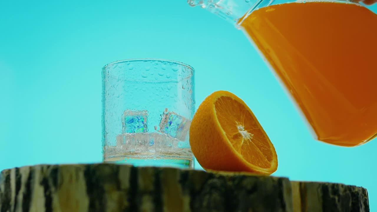 黄色的柠檬水在蓝色的背景上，倒柠檬水到杯子里，橙汁视频素材