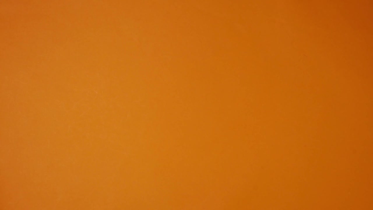 橙色背景上爬行的塑料蜘蛛。万圣节定格动画。俯视图视频素材
