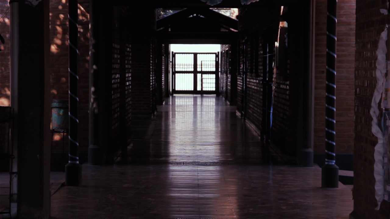 黑暗空旷的学校走廊里，门上的灯光。视频素材