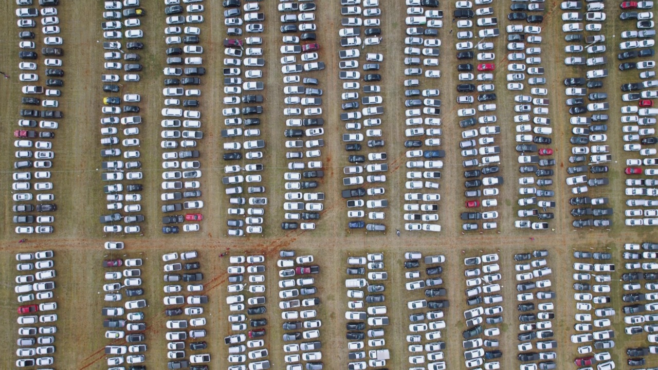 汽车配送中心的鸟瞰图，一排排的汽车停在空地上待售。进口和出口的汽车在港口排起了长队。视频素材