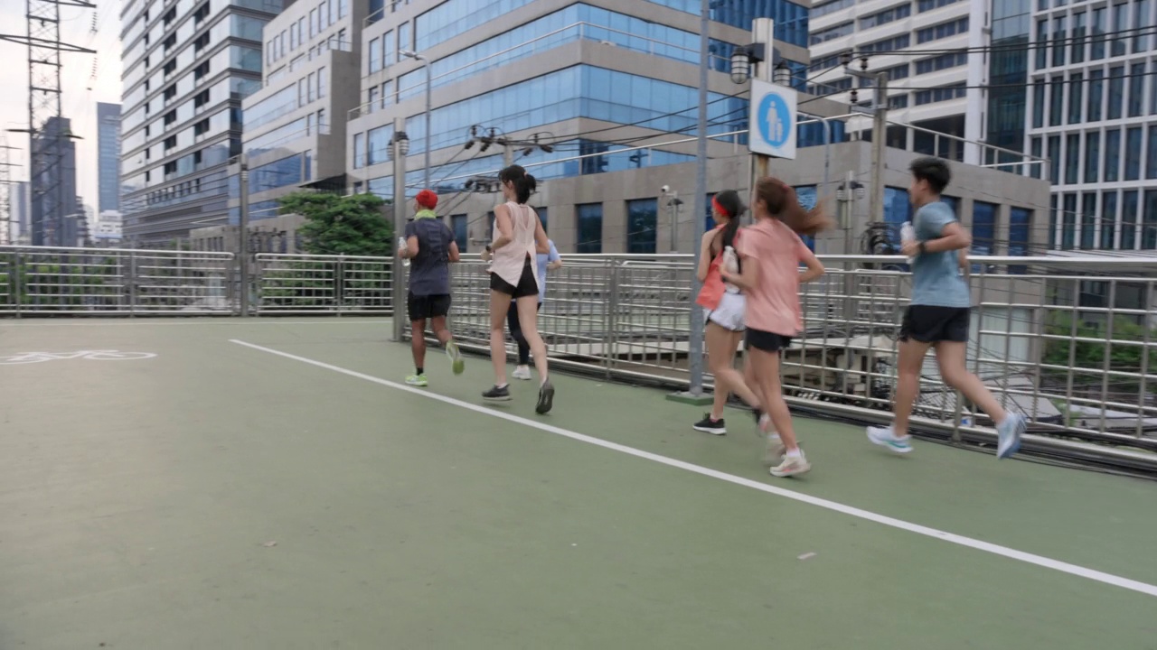 亚洲跑步团体跑步穿越立交桥现代建筑背景视频素材