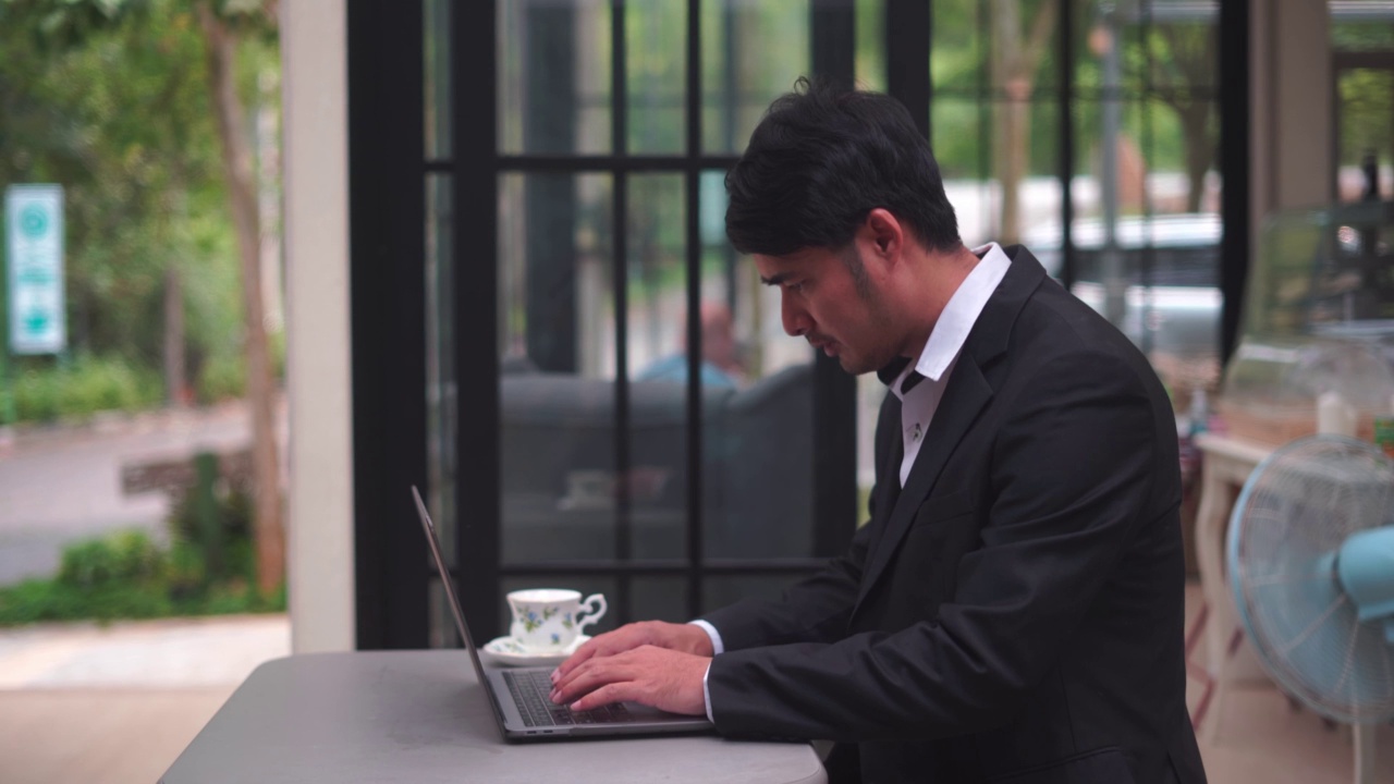 一个西装革履的商人面带微笑地使用着笔记本电脑视频下载