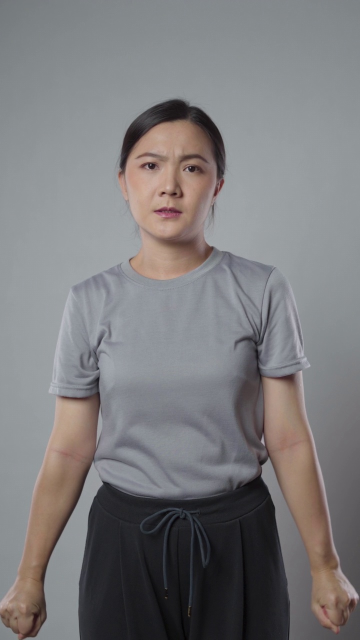 一名亚洲妇女身体疼痛，孤立地站在灰色背景上。垂直视频4k分辨率。视频下载