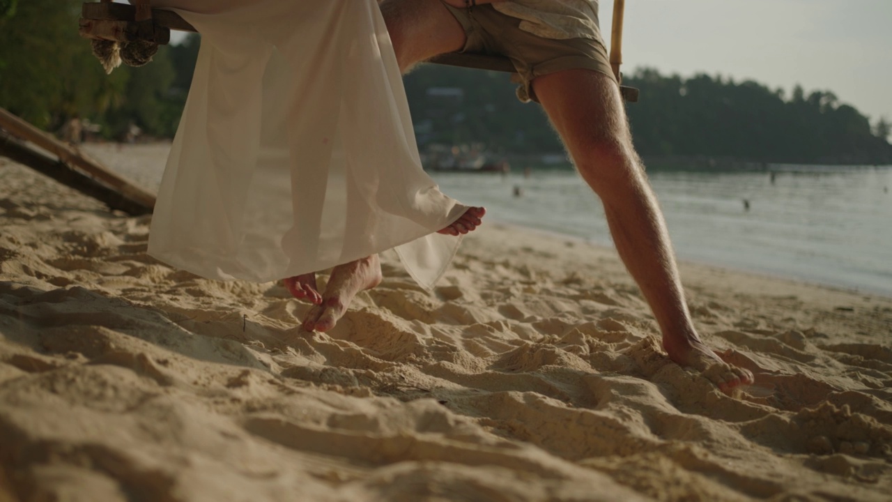 不知名的赤脚夫妇在海滩上荡秋千的B-roll视频素材