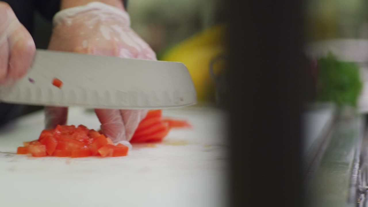 一个厨师在餐厅的厨房里切西红柿。视频下载