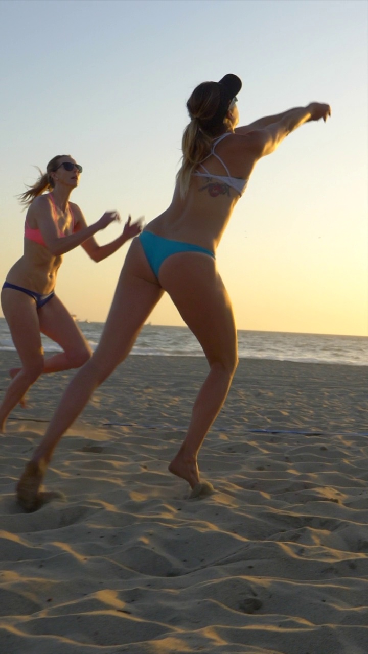 沙滩排球女子运动员日落剪影。-垂直格式-慢动作视频下载