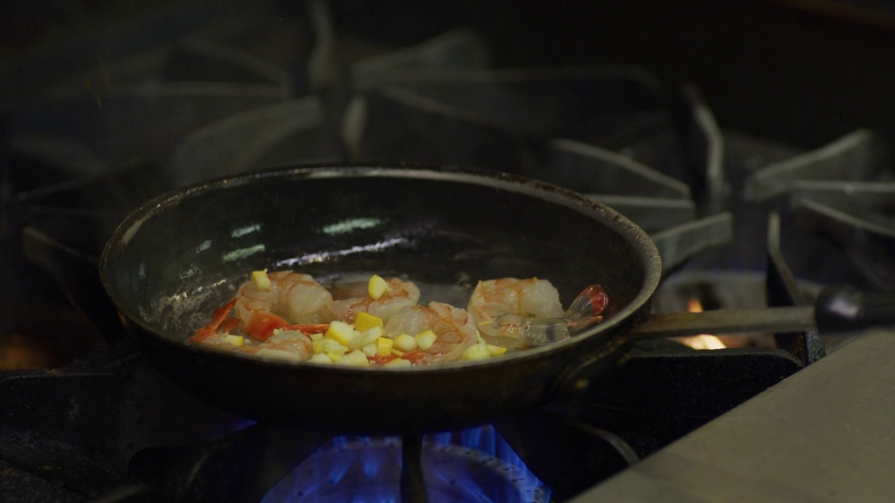 玉米粒被加入到在煤气炉上的煎锅里煮虾的盘子里。视频下载