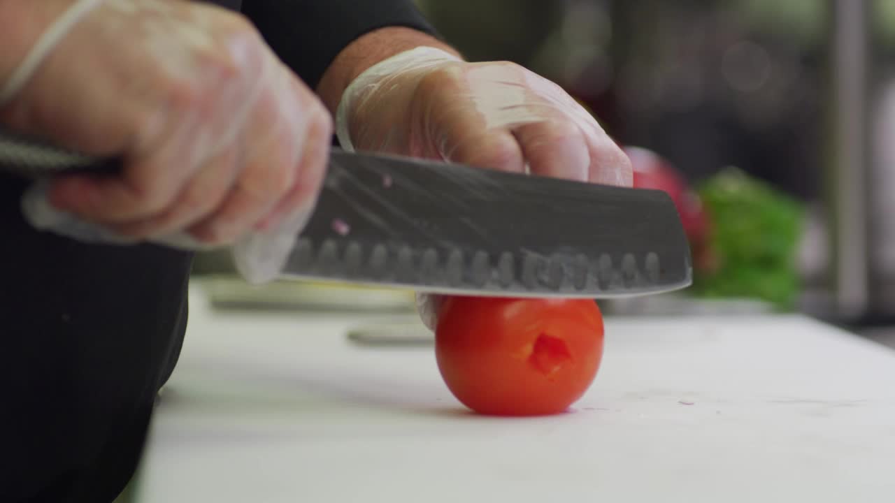 一个厨师在餐厅的厨房里切西红柿。视频下载