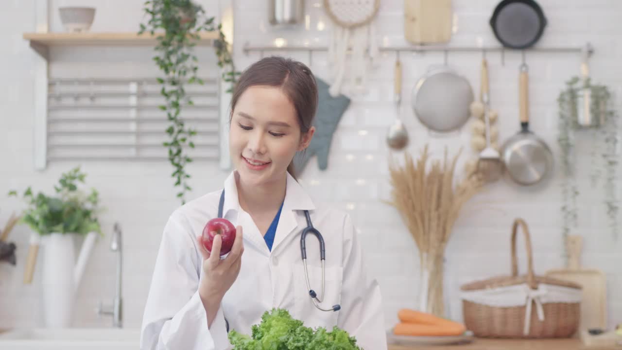营养学家亚洲妇女拿着一个苹果看着相机，健康的饮食概念视频素材