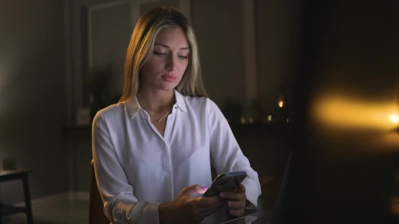 年轻女子放松地坐在家里，使用智能手机视频素材