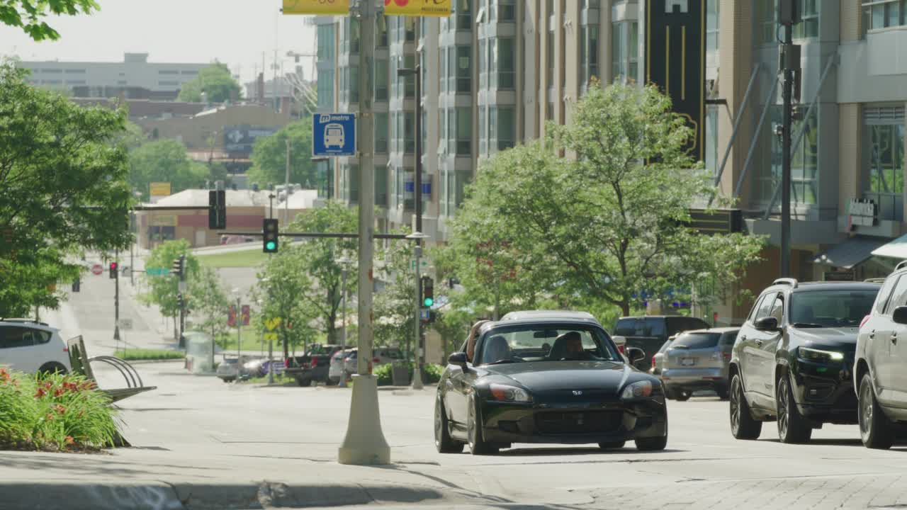 在一个现代化的市中心地区，汽车驶近并停在红绿灯前。视频下载
