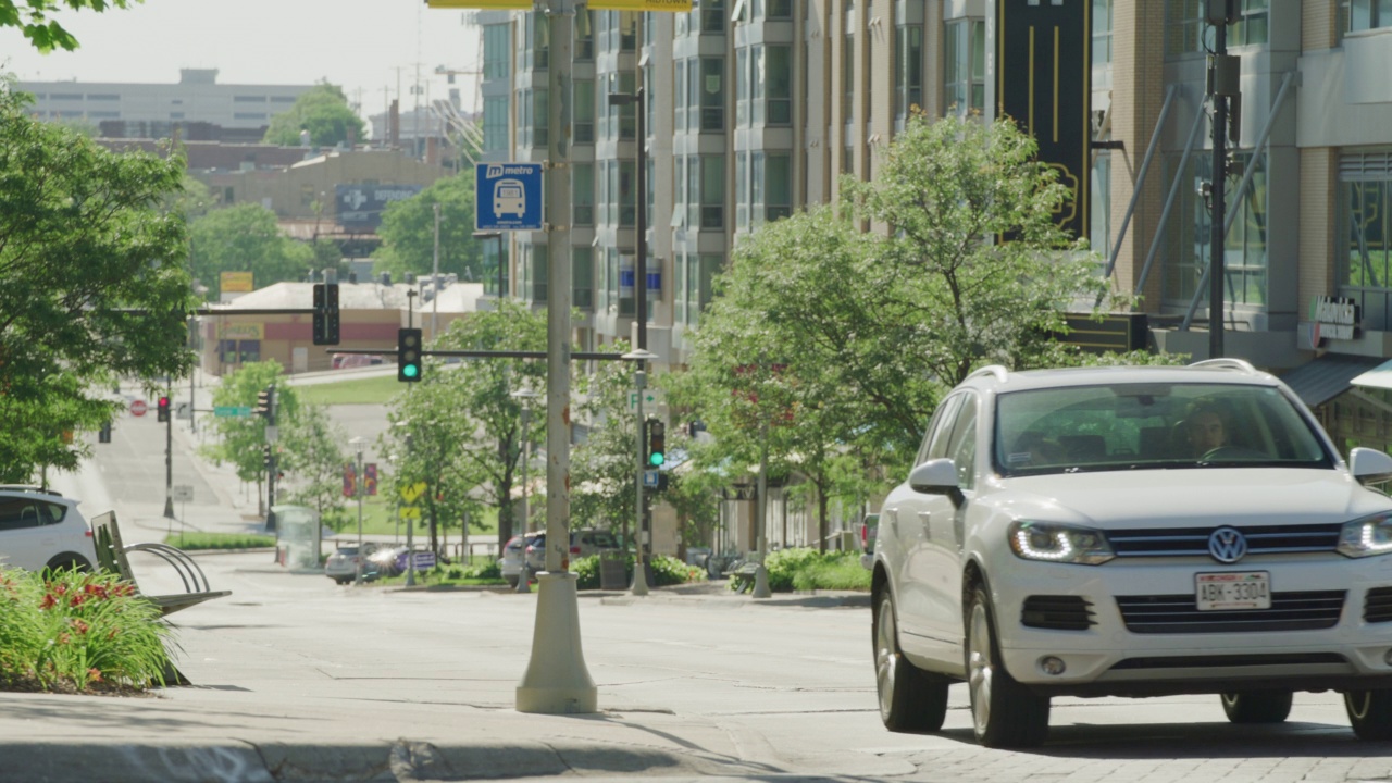 汽车停在红绿灯前，然后在一个现代化的市中心区穿过十字路口。视频下载