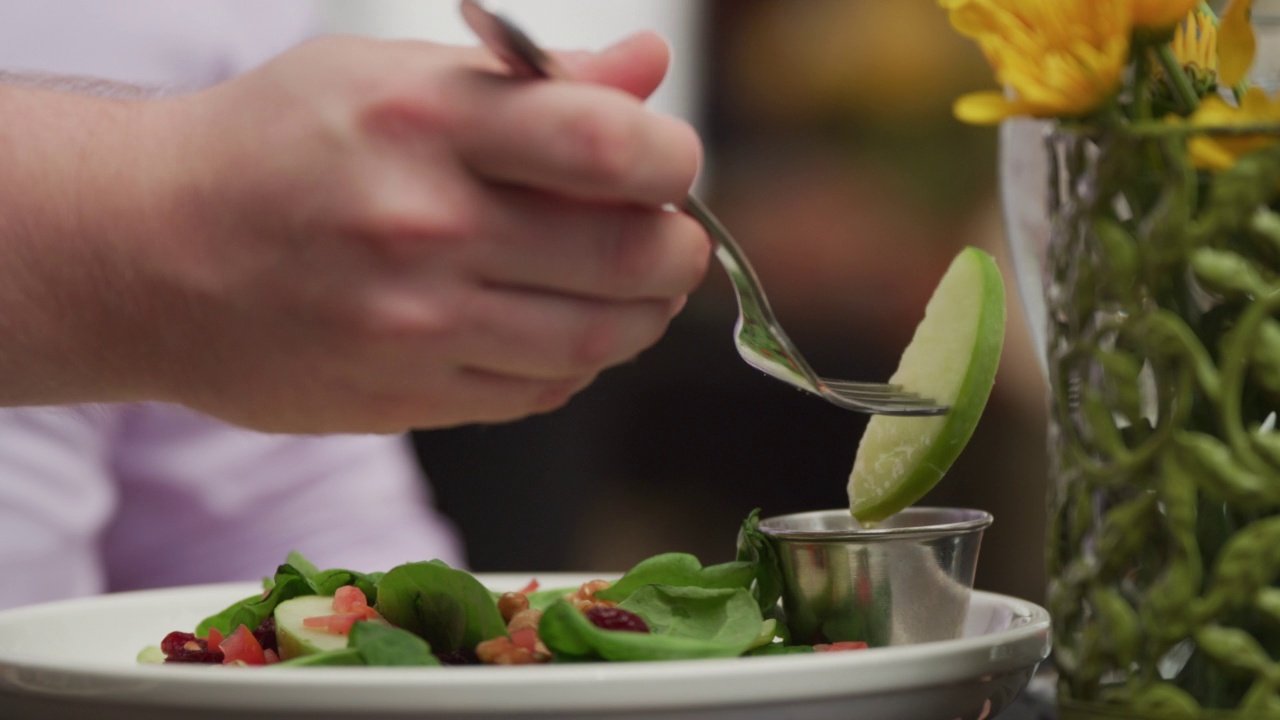 餐馆里盘子里的菠菜沙拉;一名男子将苹果片蘸上醋汁。视频下载