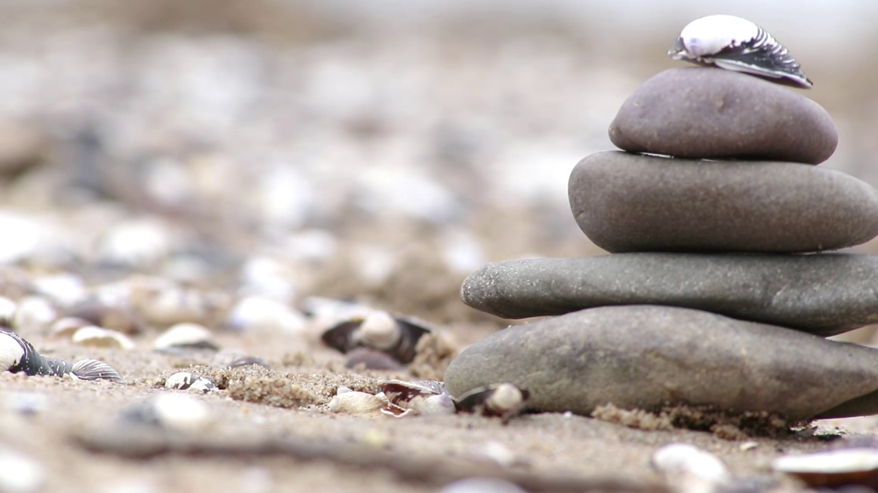 欧洲男性手工堆砌的石堆在宁静的河岸，手指与鹅卵石平静的运动，表现出自然中禅意般的和谐与放松，海岸边的石头金字塔视频素材