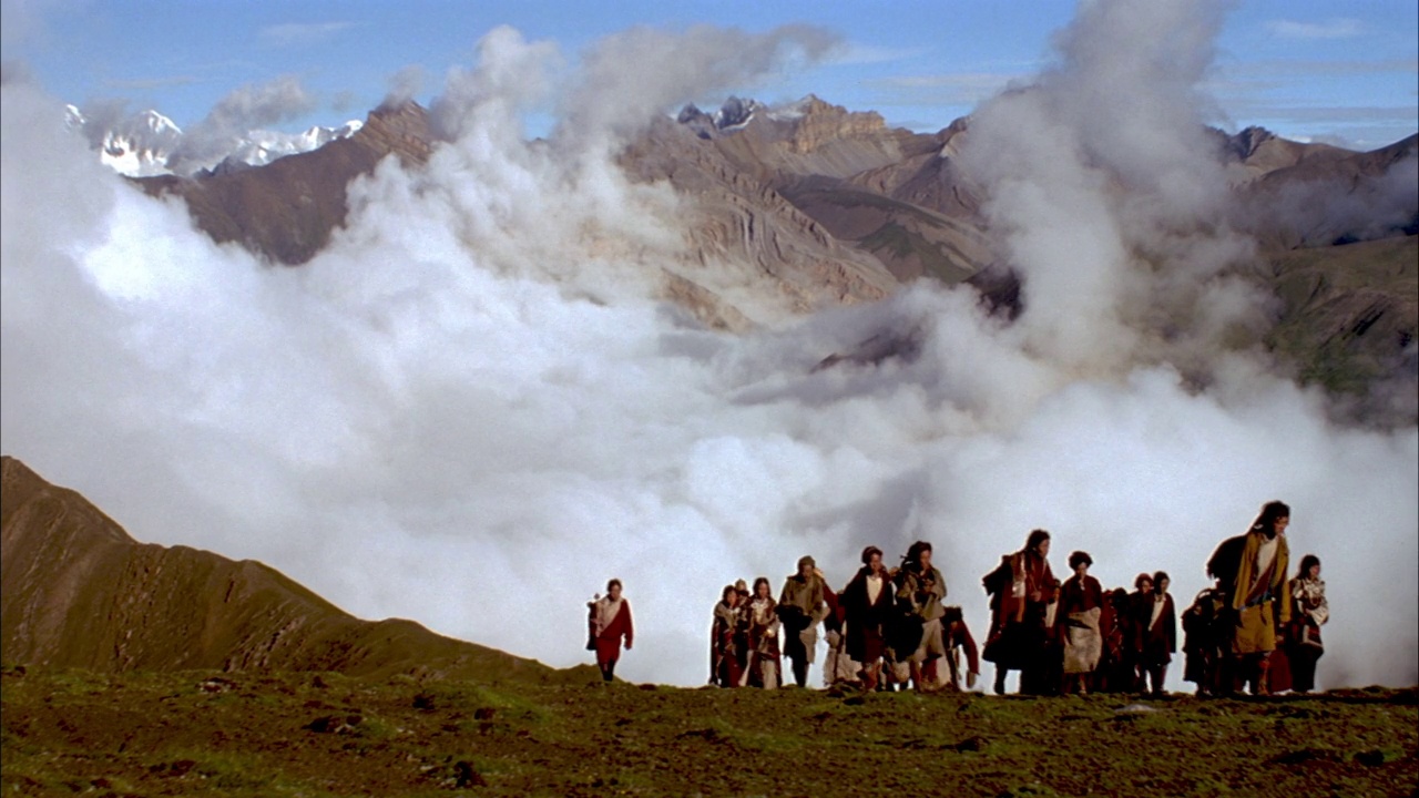 广角的一群西藏徒步旅行者或可能的登山者慢慢地从山腰后面出现。看到徒步旅行者在到达山顶后短暂地躺下祈祷，然后走到右边。看到乌云被困在崎岖的山坡之间。看到提单视频下载