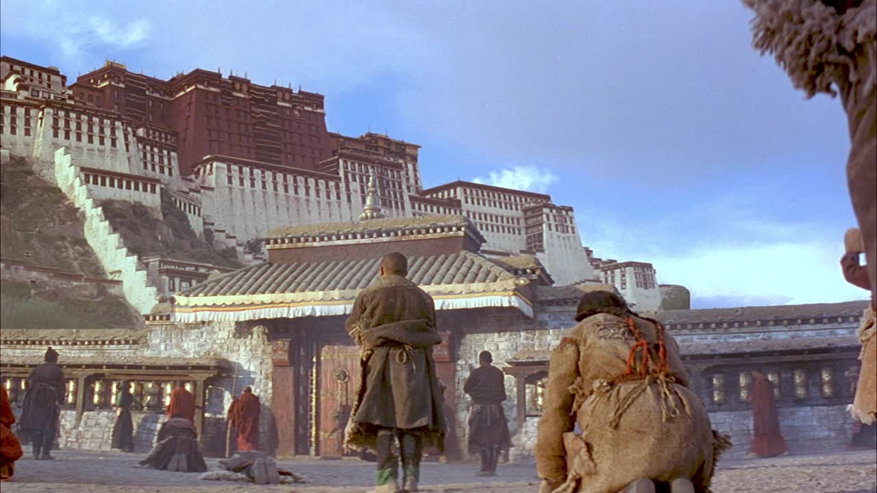 西藏平民在拉萨石山山顶向布达拉宫鞠躬、祈祷或朝拜的中角。看到平民被石墙和华丽的大门与山脚隔开。在背景中可以看到积云和蓝天。视频下载